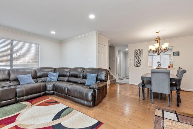 living room with crown molding, a chandelier, and light wood-type flooring