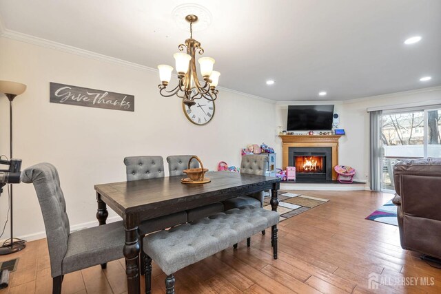 dining space featuring wood-type flooring, a notable chandelier, and ornamental molding