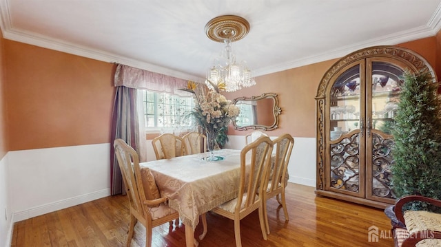 dining area with hardwood / wood-style flooring, crown molding, and an inviting chandelier