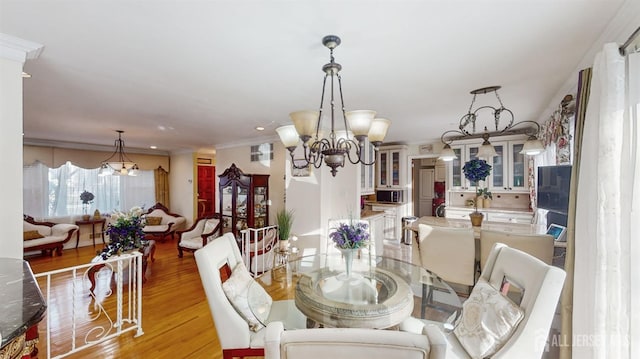 dining area with crown molding, an inviting chandelier, and light hardwood / wood-style floors