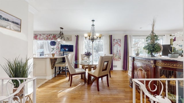 dining space featuring ornamental molding, light hardwood / wood-style floors, and a chandelier