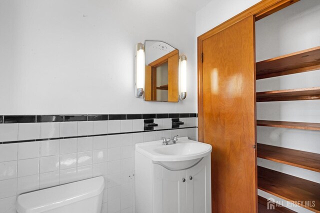 bathroom with vanity, tile walls, and toilet