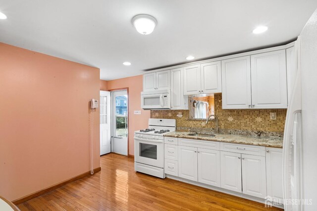 kitchen featuring white appliances, white cabinets, sink, decorative backsplash, and light wood-type flooring