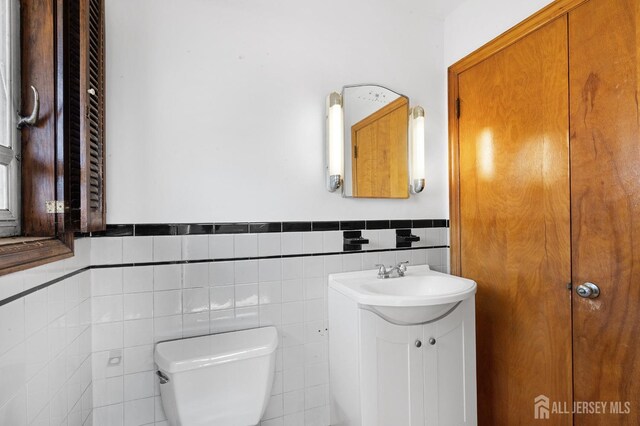 bathroom featuring vanity, tile walls, and toilet