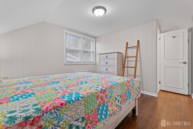 bedroom featuring wood-type flooring, lofted ceiling, and wood walls