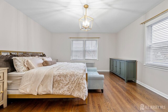 bedroom featuring hardwood / wood-style floors, radiator heating unit, and an inviting chandelier