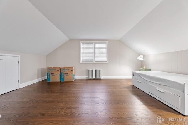 unfurnished bedroom featuring dark hardwood / wood-style flooring, radiator, and vaulted ceiling