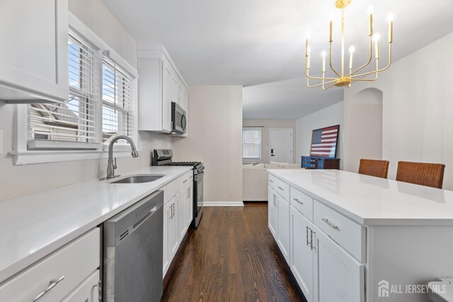 kitchen with pendant lighting, white cabinets, sink, and appliances with stainless steel finishes