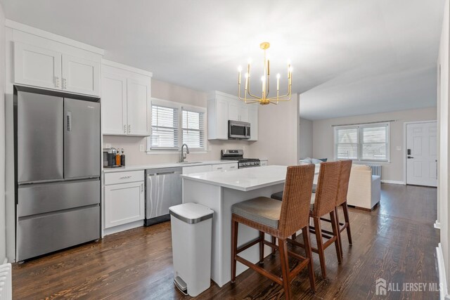 kitchen with white cabinets, decorative light fixtures, a kitchen island, and stainless steel appliances