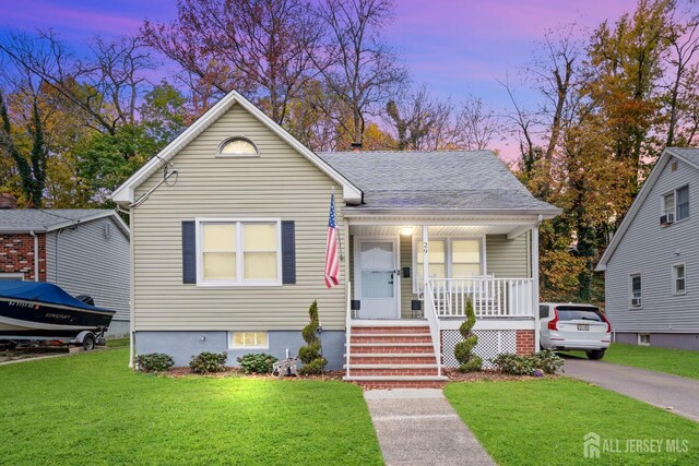 bungalow featuring a porch and a lawn