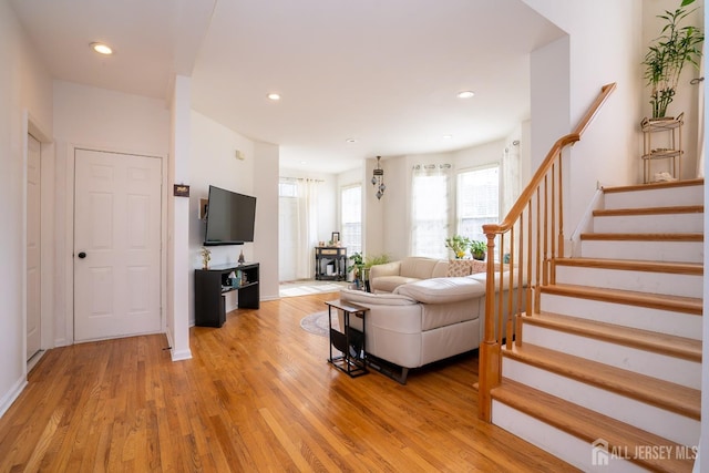 living room with light wood finished floors, recessed lighting, and stairs