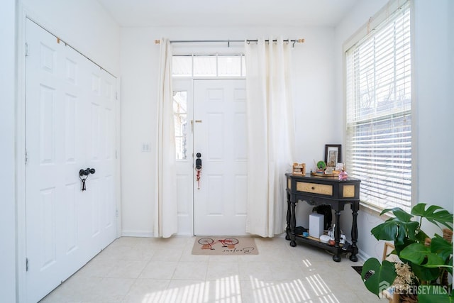 entryway featuring plenty of natural light, light tile patterned flooring, and baseboards