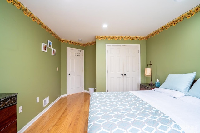 bedroom with a closet, baseboards, light wood-style floors, and visible vents