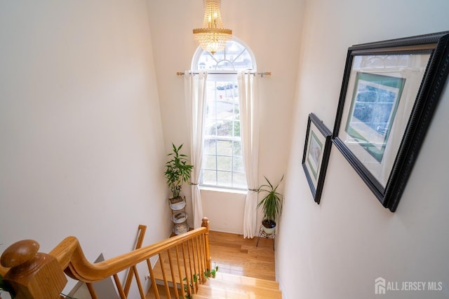 interior space with an upstairs landing, a notable chandelier, and light wood-style floors