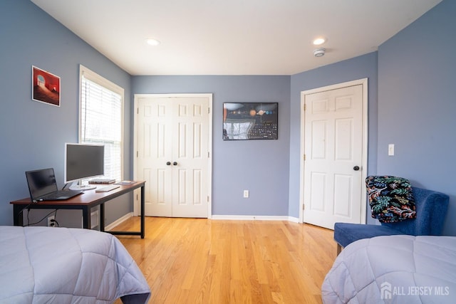 bedroom featuring recessed lighting, light wood-type flooring, baseboards, and a closet