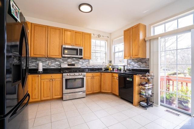 kitchen with visible vents, black appliances, backsplash, dark countertops, and light tile patterned floors