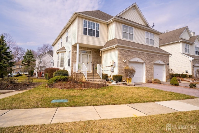 view of front of property featuring a front lawn, brick siding, a garage, and driveway