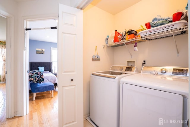 laundry room featuring washing machine and clothes dryer, laundry area, and light wood finished floors