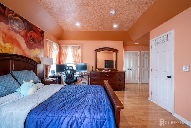 bedroom with recessed lighting, baseboards, a raised ceiling, and wood finished floors