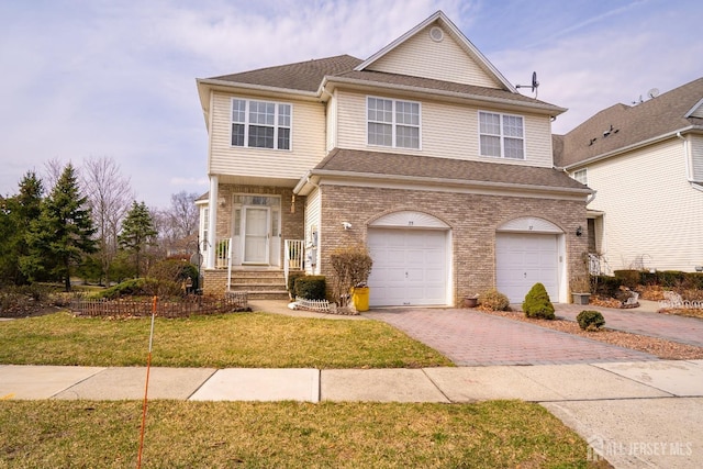 view of front of property featuring a front yard, decorative driveway, brick siding, and a garage