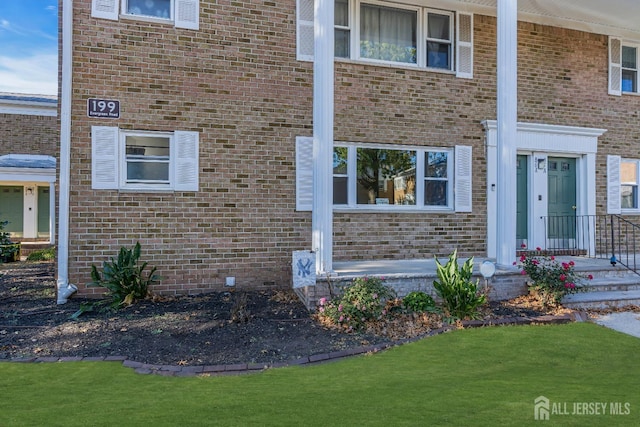 property entrance with brick siding and a yard