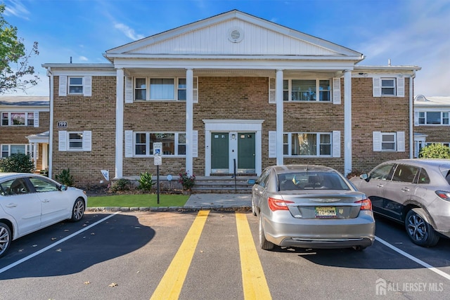 view of property featuring entry steps, uncovered parking, and brick siding