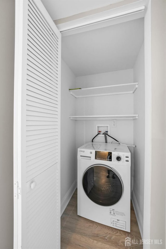 washroom with laundry area, dark wood finished floors, washer / dryer, and baseboards