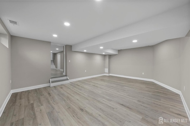 finished below grade area featuring light wood-type flooring, visible vents, and baseboards