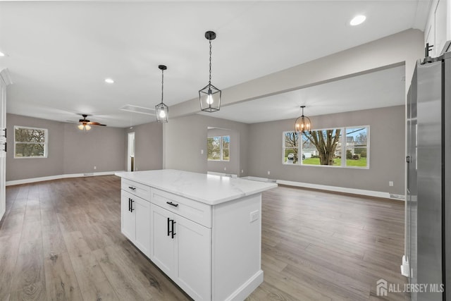 kitchen featuring white cabinets, a center island, open floor plan, and decorative light fixtures