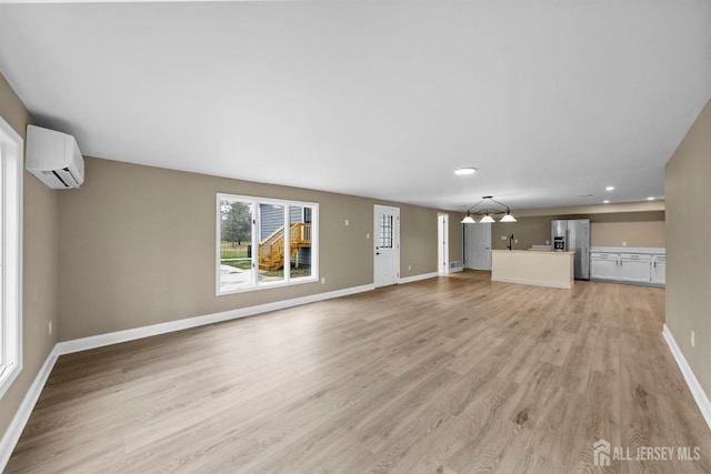 unfurnished living room featuring light wood-style flooring, baseboards, an AC wall unit, and recessed lighting