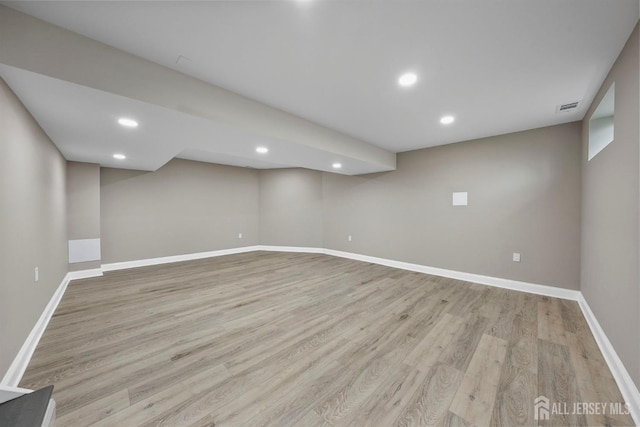 finished basement featuring baseboards, recessed lighting, visible vents, and light wood-style floors