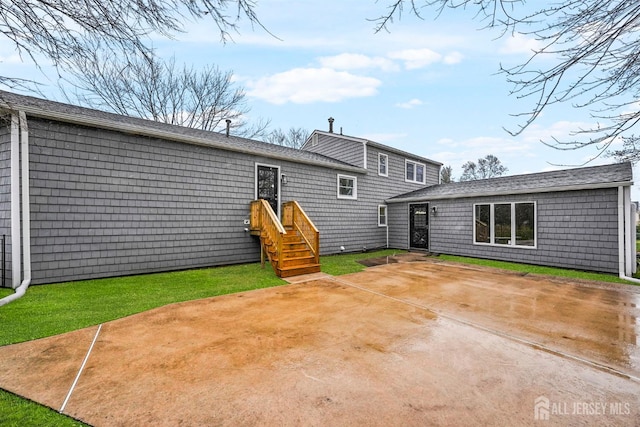 back of house with entry steps, a patio area, and a lawn