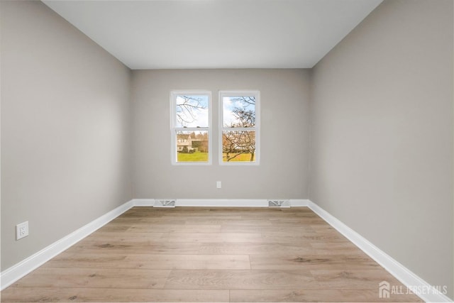 unfurnished room with light wood-type flooring, baseboards, and visible vents