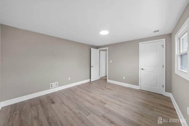 unfurnished bedroom featuring light wood finished floors, baseboards, and visible vents