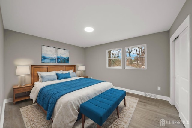 bedroom featuring a closet, visible vents, baseboards, and wood finished floors