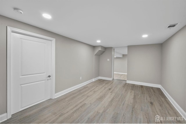 finished below grade area with light wood-type flooring, visible vents, baseboards, and recessed lighting