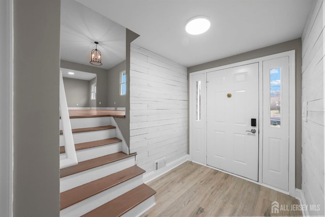 entrance foyer with light wood-type flooring, baseboards, stairs, and visible vents