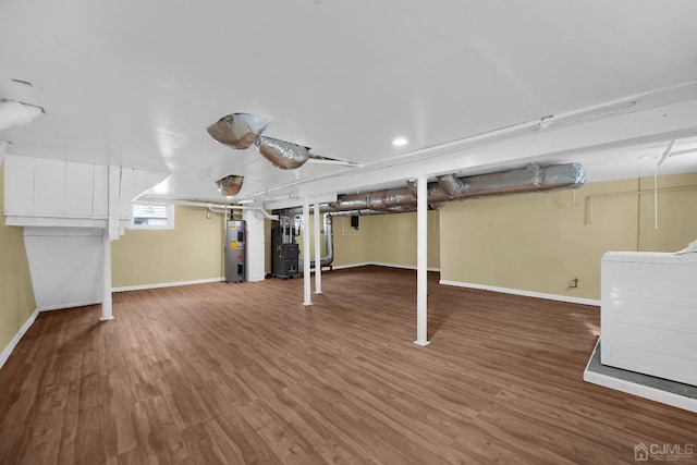 basement with heating unit, water heater, washer / dryer, and wood-type flooring