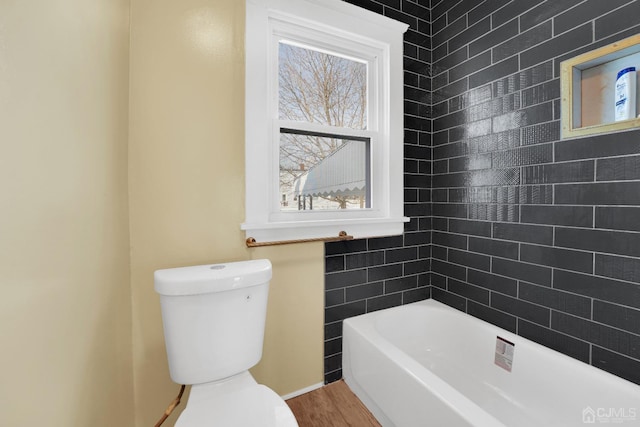 bathroom with toilet, a tub, and wood-type flooring