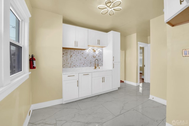 kitchen with backsplash, sink, and white cabinetry