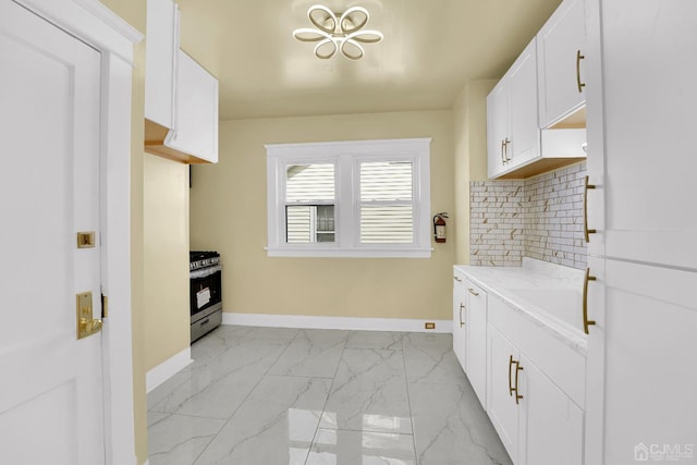 kitchen with gas range, sink, white cabinetry, and tasteful backsplash