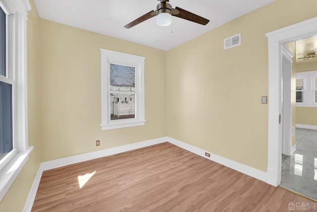 spare room with light wood-type flooring, ceiling fan, and plenty of natural light