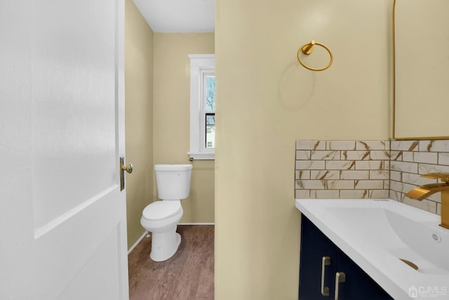 bathroom with toilet, wood-type flooring, vanity, and tasteful backsplash