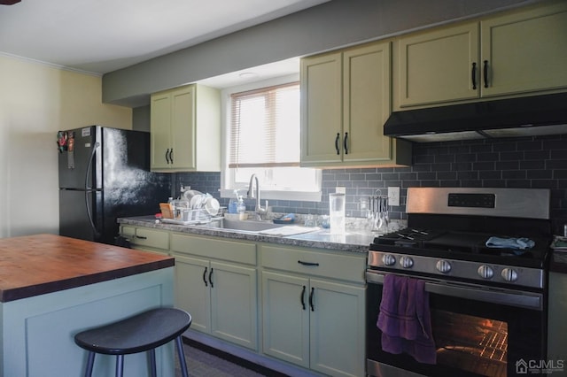 kitchen featuring sink, stainless steel gas stove, black refrigerator, and tasteful backsplash