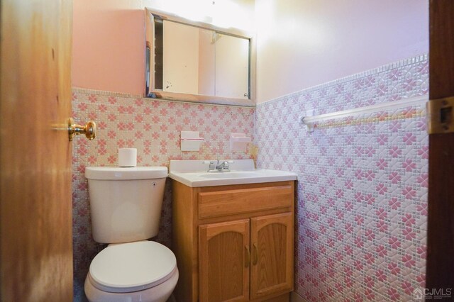 bathroom with vanity, toilet, and tile walls