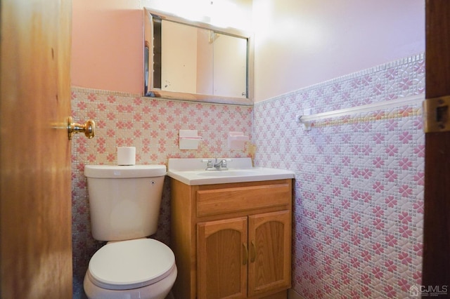 bathroom featuring tile walls, vanity, and toilet