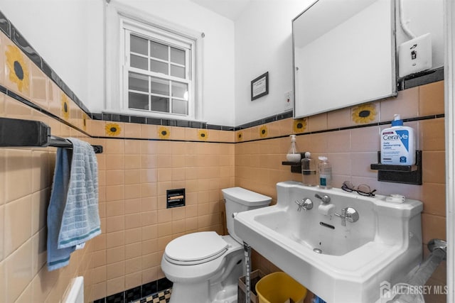 286 Easton Ave, New Brunswick, NJ 08901 - half bathroom featuring tile walls, toilet, a sink, and a wainscoted wall