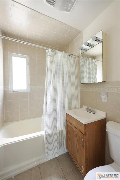 995 Old Bridge Tpke, East Brunswick, NJ 08816 - bathroom featuring vanity, shower / bath combination with curtain, tile patterned flooring, and tile walls