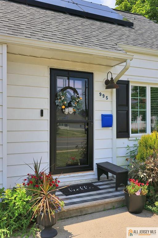 995 Old Bridge Tpke, East Brunswick, NJ 08816 - view of exterior entry with a shingled roof and solar panels