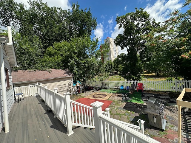 wooden terrace with a fenced backyard and area for grilling